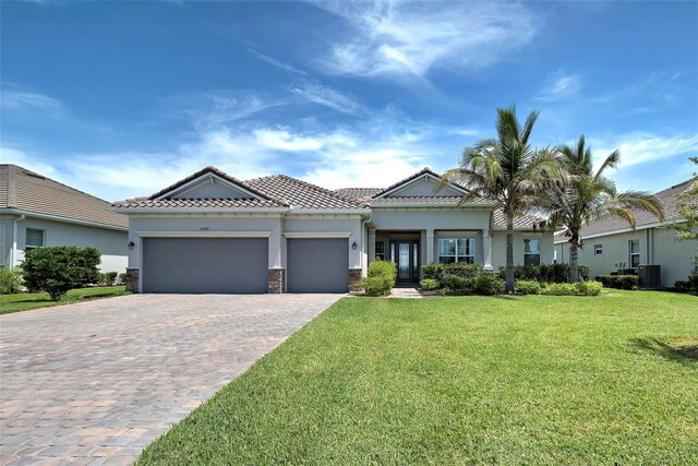 15240 Spanish Point Dr, Port Charlotte, FL 33981 - view of front facade with stucco siding, decorative driveway, a front yard, a tile roof, and a garage