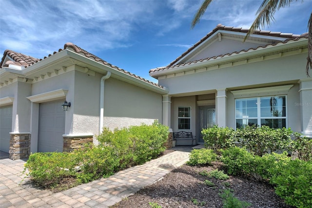 15240 Spanish Point Dr, Port Charlotte, FL 33981 - doorway to property with a tiled roof, stucco siding, stone siding, and an attached garage