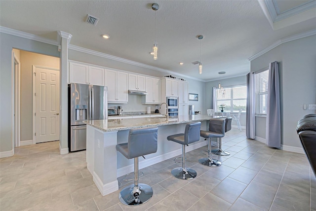 15240 Spanish Point Dr, Port Charlotte, FL 33981 - kitchen with under cabinet range hood, a kitchen breakfast bar, white cabinetry, and appliances with stainless steel finishes