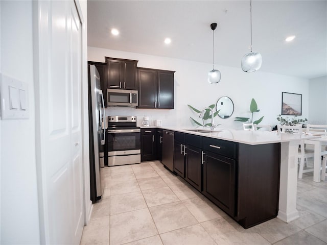 kitchen with sink, appliances with stainless steel finishes, pendant lighting, and light tile patterned floors