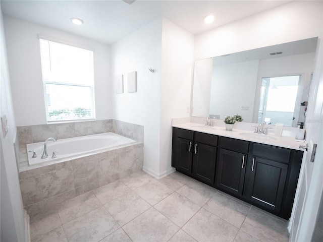 bathroom with plenty of natural light, tiled tub, dual vanity, and tile patterned floors