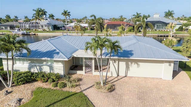 view of front facade with a residential view, metal roof, a water view, decorative driveway, and stucco siding