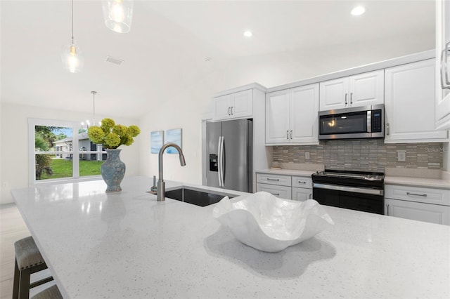 kitchen featuring appliances with stainless steel finishes, pendant lighting, sink, white cabinets, and light stone counters