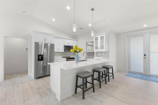 kitchen with appliances with stainless steel finishes, pendant lighting, a breakfast bar area, white cabinets, and french doors