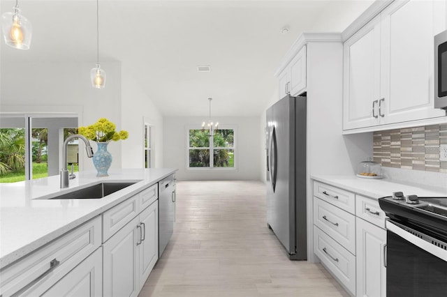 kitchen featuring sink, white cabinetry, backsplash, hanging light fixtures, and stainless steel appliances