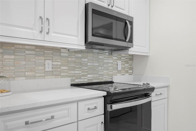 kitchen with range with electric stovetop, white cabinetry, light stone counters, and decorative backsplash