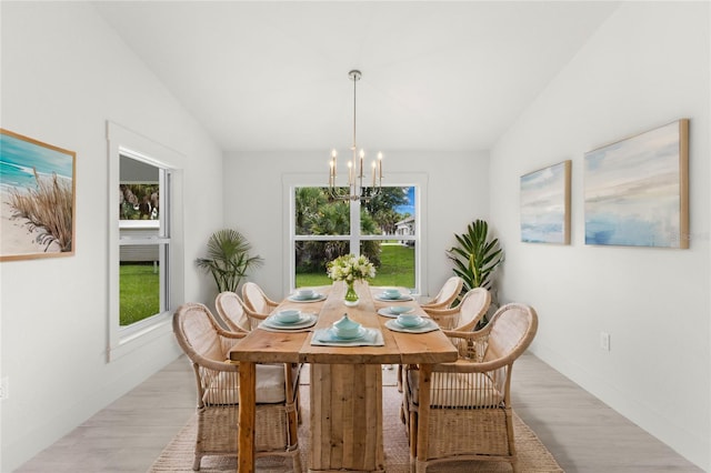 dining room with lofted ceiling, a chandelier, light wood-type flooring, and a wealth of natural light