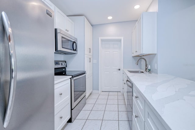 kitchen featuring white cabinetry, light stone counters, light tile patterned floors, sink, and stainless steel appliances