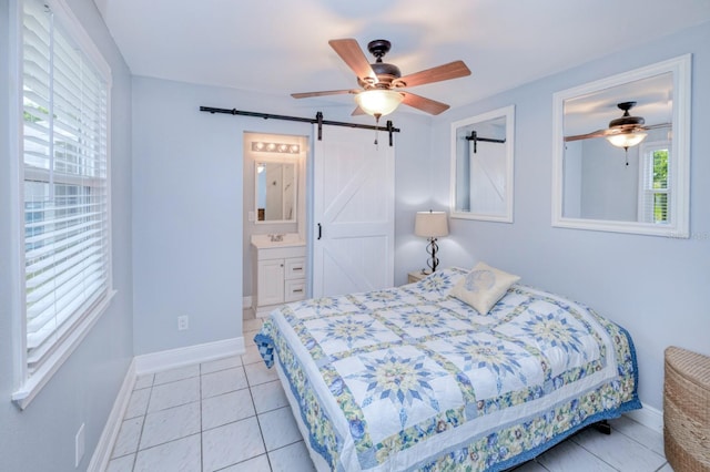 bedroom with ceiling fan, a barn door, light tile patterned flooring, and ensuite bathroom