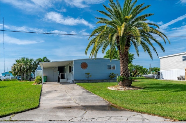 manufactured / mobile home with a front yard, concrete driveway, and an attached carport