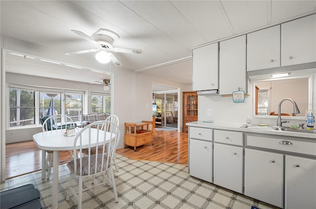 kitchen featuring white cabinets, sink, light wood-type flooring, and ceiling fan