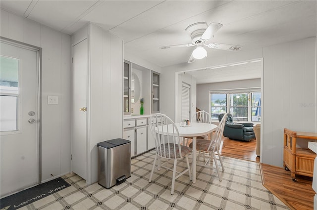 dining room with built in shelves, ceiling fan, and light wood-type flooring