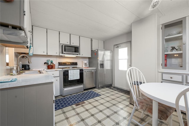 kitchen with gray cabinets, sink, light tile patterned flooring, and stainless steel appliances