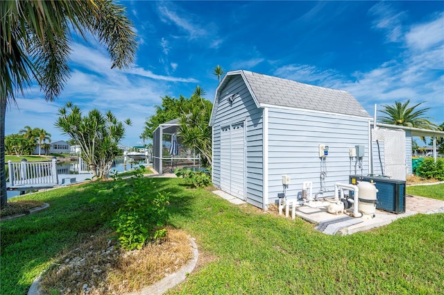 view of side of property featuring a storage shed, central AC unit, a water view, and a lawn