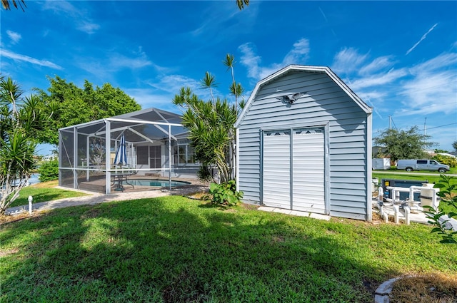 rear view of property featuring a yard, a storage shed, and a lanai