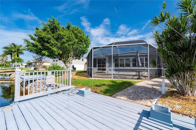 wooden deck with glass enclosure, a patio, a water view, and a swimming pool