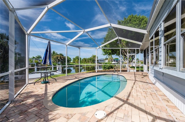 view of pool with a water view, glass enclosure, and a patio area