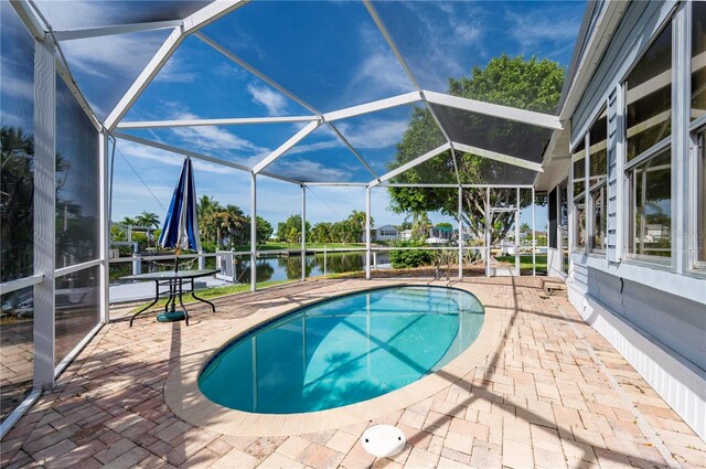 outdoor pool with a patio area, glass enclosure, and a water view