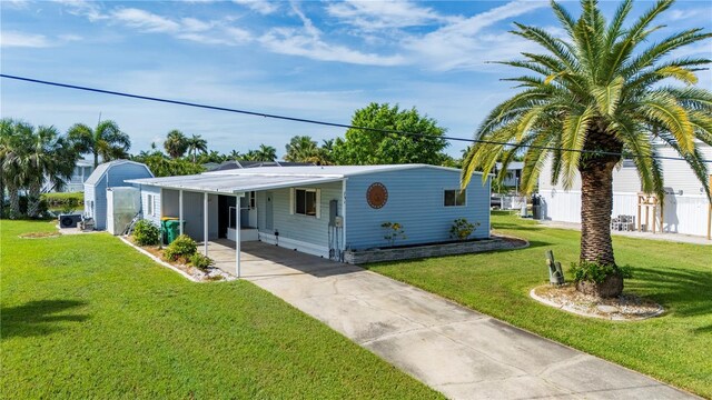 view of front of home featuring concrete driveway, an attached carport, and a front yard