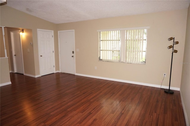 empty room featuring lofted ceiling, wood-type flooring, and a textured ceiling