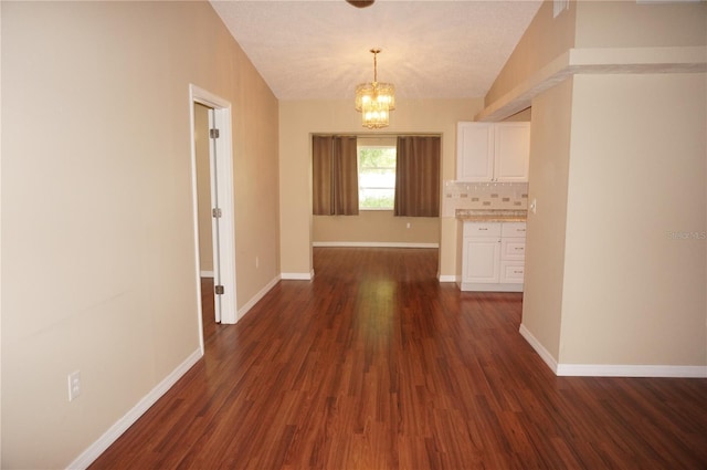 interior space featuring vaulted ceiling, dark hardwood / wood-style flooring, and a notable chandelier