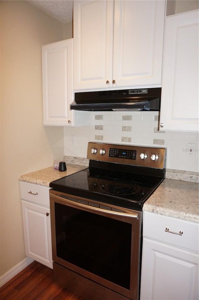 kitchen with ventilation hood, stainless steel range with electric stovetop, dark hardwood / wood-style floors, and white cabinets