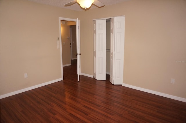 unfurnished bedroom with dark hardwood / wood-style floors, ceiling fan, and a closet