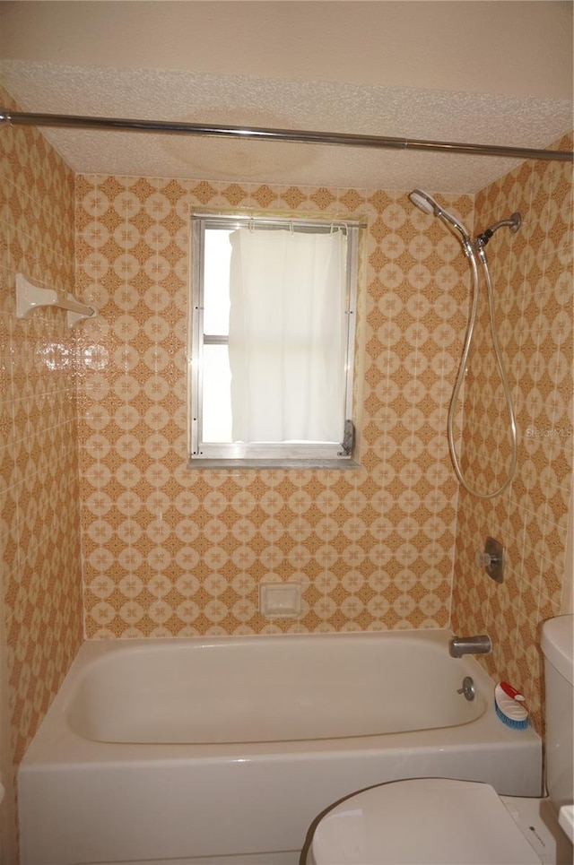 bathroom featuring tiled shower / bath combo and toilet