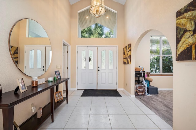 entrance foyer featuring light hardwood / wood-style floors, a notable chandelier, and a high ceiling