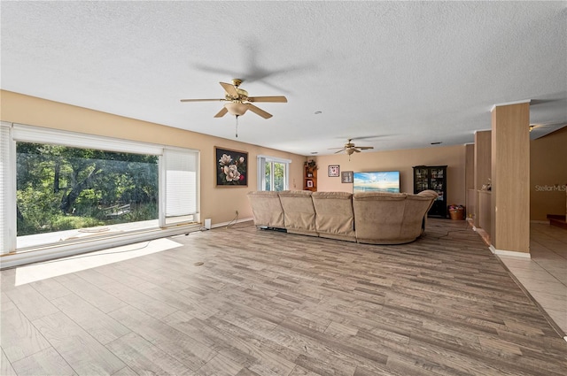 unfurnished living room featuring light hardwood / wood-style flooring, a textured ceiling, and ceiling fan