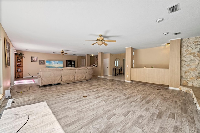 living room with light wood-type flooring, ceiling fan, and a textured ceiling