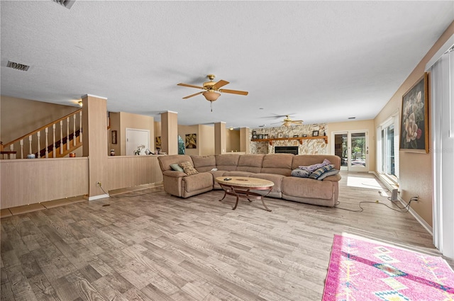 living room featuring a fireplace, a textured ceiling, hardwood / wood-style floors, and ceiling fan