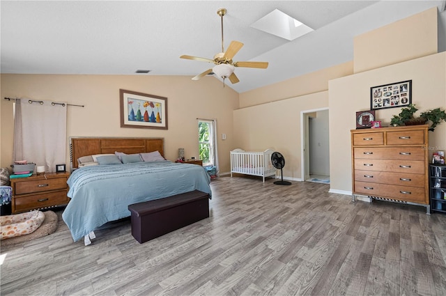 bedroom with high vaulted ceiling, ceiling fan, wood-type flooring, and a skylight