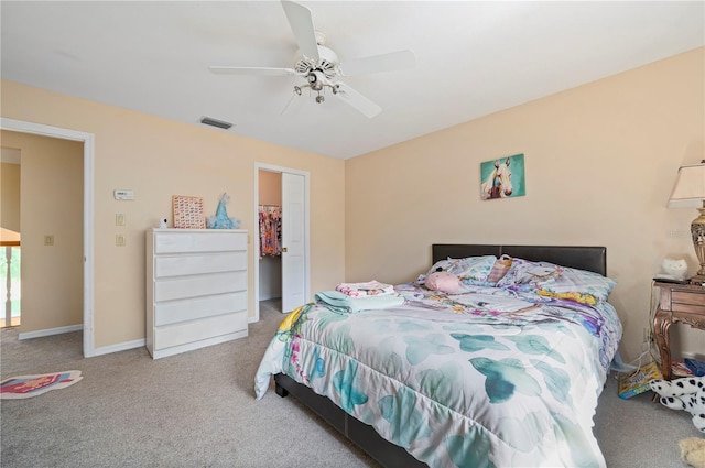 bedroom featuring light carpet, ceiling fan, a walk in closet, and a closet