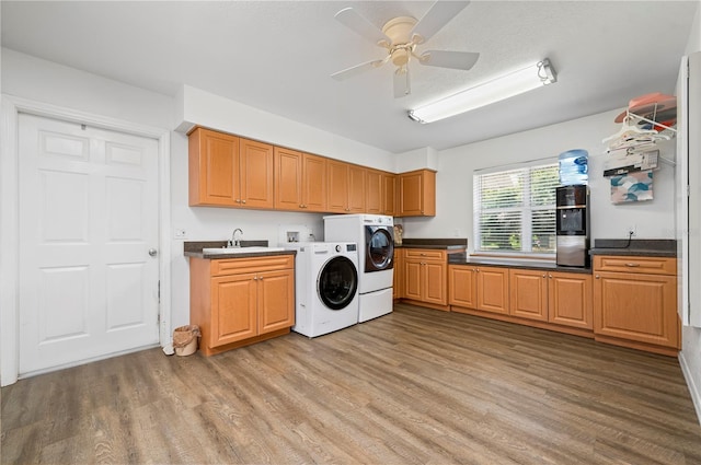 laundry room with light hardwood / wood-style flooring, ceiling fan, washing machine and clothes dryer, cabinets, and sink