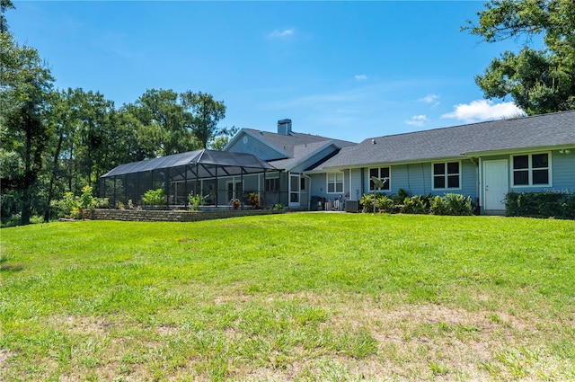 rear view of house with glass enclosure, central air condition unit, and a yard