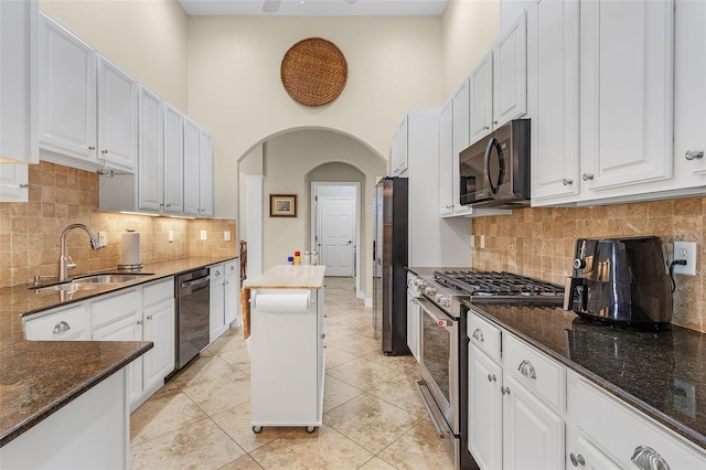 kitchen with sink, appliances with stainless steel finishes, backsplash, and a high ceiling