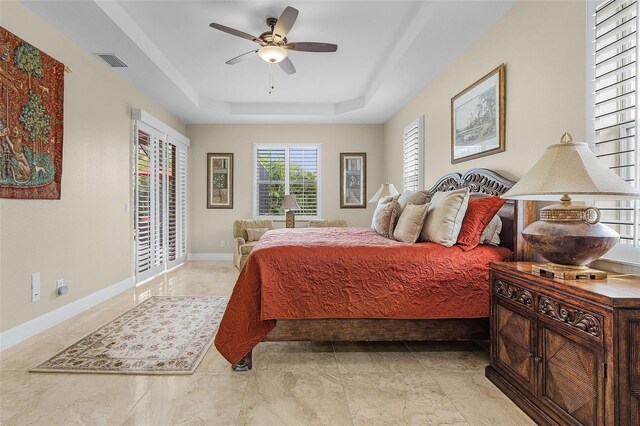 tiled bedroom featuring ceiling fan and a raised ceiling