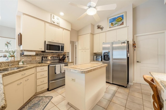 kitchen featuring vaulted ceiling, appliances with stainless steel finishes, sink, a kitchen island, and decorative backsplash