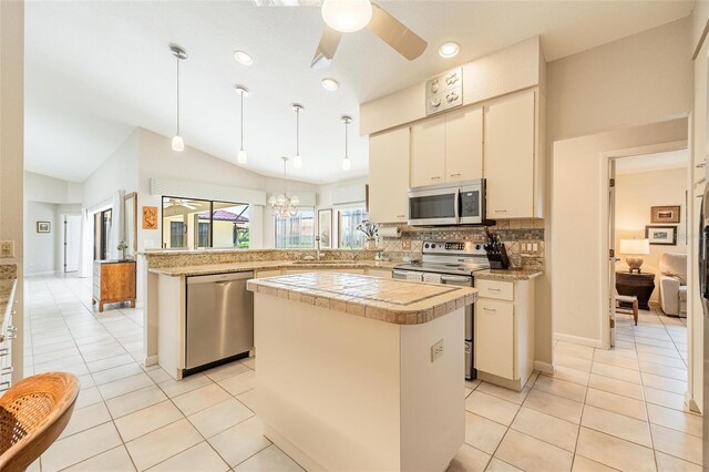 kitchen with tasteful backsplash, a kitchen island, decorative light fixtures, stainless steel appliances, and lofted ceiling