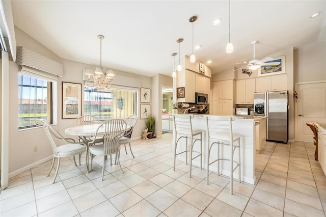 kitchen with appliances with stainless steel finishes, pendant lighting, vaulted ceiling, ceiling fan with notable chandelier, and light tile patterned flooring