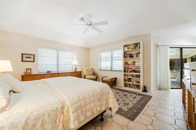 bedroom featuring ceiling fan, a raised ceiling, access to outside, and multiple windows