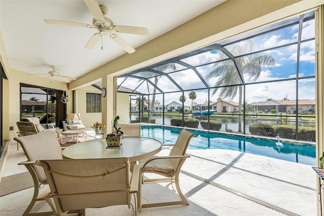 view of pool with a water view, a patio area, ceiling fan, and a lanai