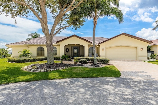 mediterranean / spanish-style house with decorative driveway, an attached garage, a front yard, and stucco siding