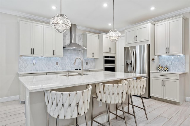 kitchen with stainless steel appliances, tasteful backsplash, wall chimney exhaust hood, and a center island with sink