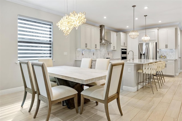 dining space with an inviting chandelier, light hardwood / wood-style floors, sink, and ornamental molding