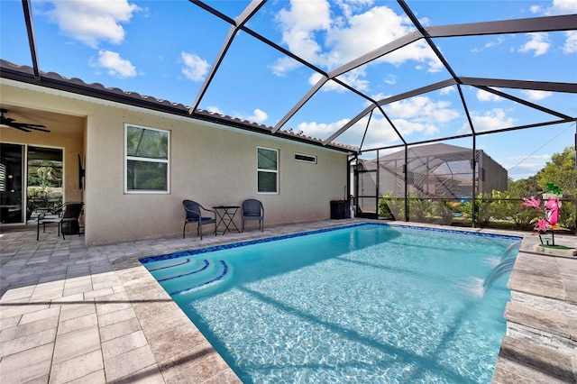 view of pool with pool water feature, glass enclosure, a patio, and ceiling fan