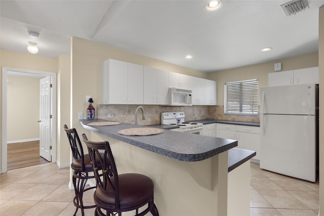 kitchen featuring light tile patterned flooring, white cabinetry, white appliances, and kitchen peninsula