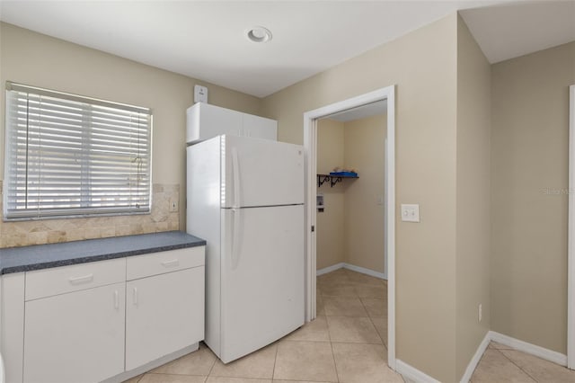 kitchen with light tile patterned flooring, white fridge, and white cabinets