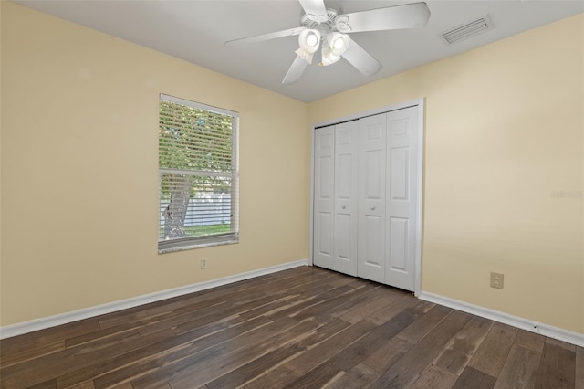 unfurnished bedroom with ceiling fan, dark hardwood / wood-style flooring, and a closet